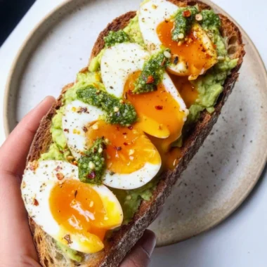 Avocado Pesto Toast topped with eggs, fresh herbs, and spices.