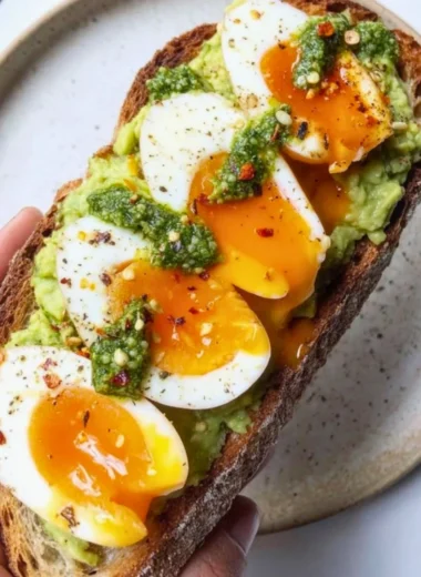 Avocado Pesto Toast topped with eggs, fresh herbs, and spices.