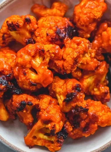 Bowl of Easy Buffalo Cauliflower with spicy sauce and garnishes
