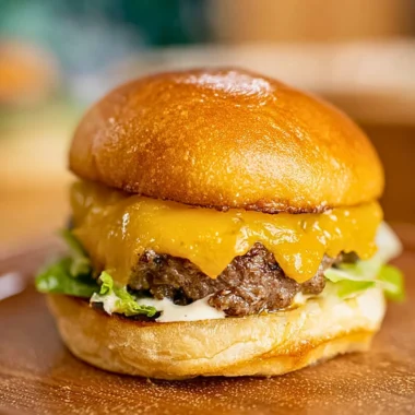 Homemade smash burger on a grill with toppings.