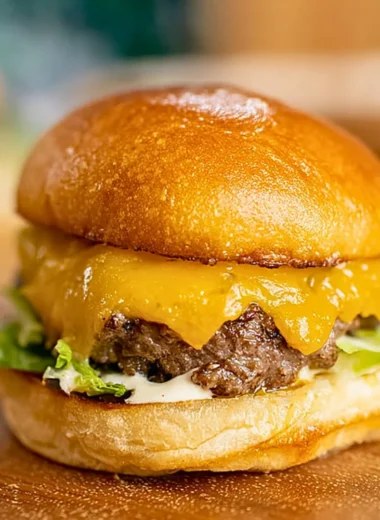 Homemade smash burger on a grill with toppings.