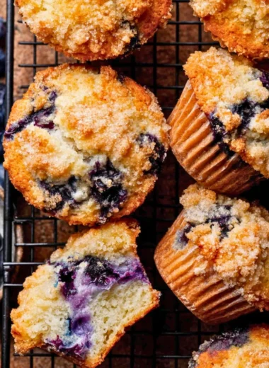 Bakery style blueberry muffins fresh out of the oven with blueberries on top