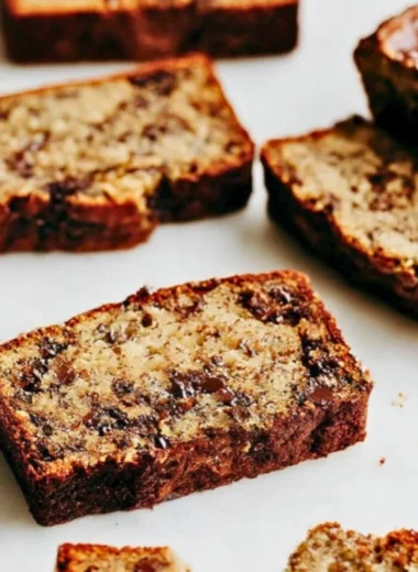 Deliciously baked chocolate chip banana bread loaf on a wooden cutting board
