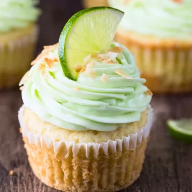 Coconut cupcakes topped with lime buttercream frosting on a decorative plate.