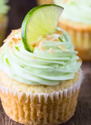 Coconut cupcakes topped with lime buttercream frosting on a decorative plate.