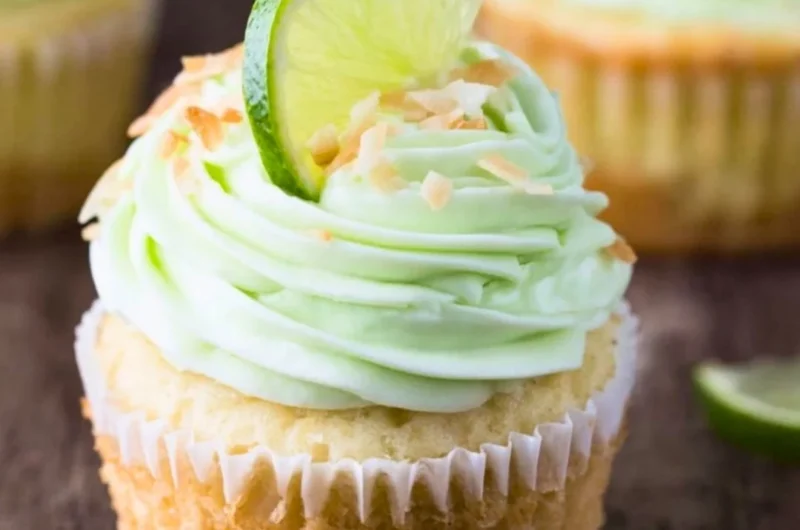 Coconut cupcakes topped with lime buttercream frosting on a decorative plate.