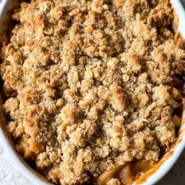 Bowl of gluten-free apple crisp with oats and cinnamon on a wooden table