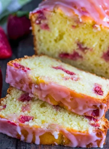 Slice of homemade strawberry pound cake topped with fresh strawberries and whipped cream