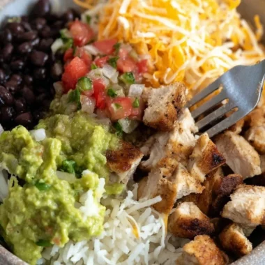 Grilled chicken burrito bowl with rice and beans, fresh ingredients, and vibrant colors.