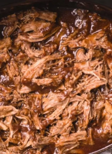 Delicious BBQ pulled pork made in a slow cooker, served with buns and coleslaw