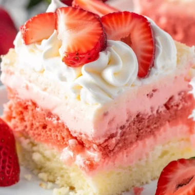 Slice of Strawberry Cheesecake Poke Cake on a plate with fresh strawberries.