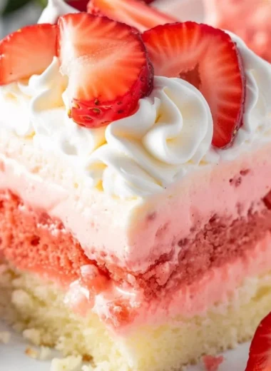 Slice of Strawberry Cheesecake Poke Cake on a plate with fresh strawberries.