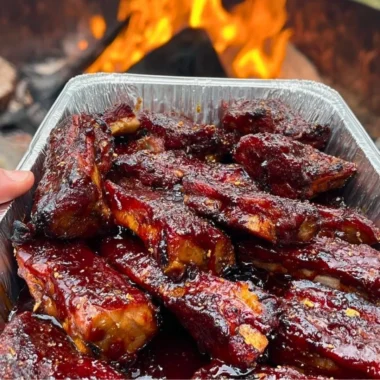 Delicious BBQ ribs on a plate, garnished with fresh herbs and sauces.