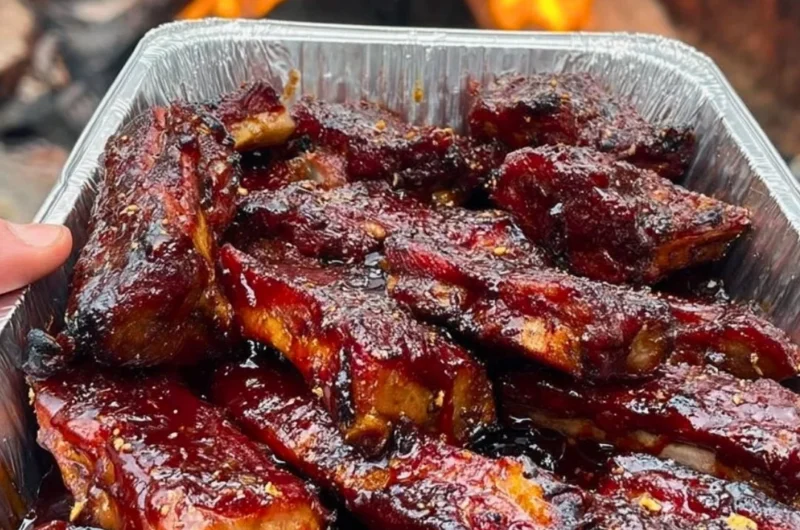 Delicious BBQ ribs on a plate, garnished with fresh herbs and sauces.