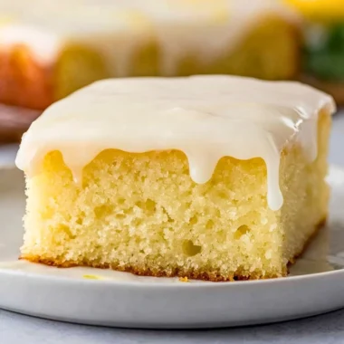 Delicious lemonade poke cake topped with fresh lemon slices and whipped cream