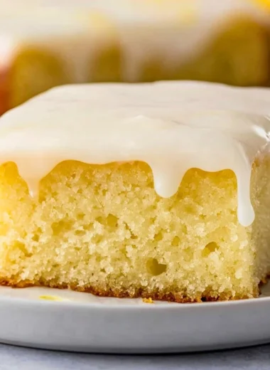 Delicious lemonade poke cake topped with fresh lemon slices and whipped cream