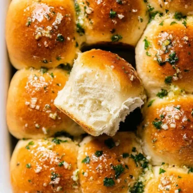 Homemade garlic bread rolls served on a wooden platter with butter.