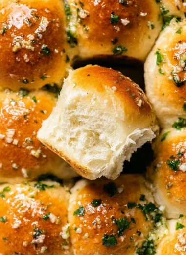 Homemade garlic bread rolls served on a wooden platter with butter.