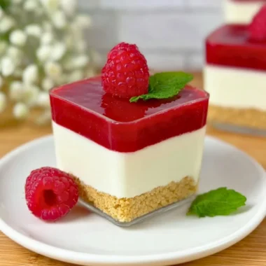 Layered Raspberry Cheesecake in a glass with fresh raspberries and cream