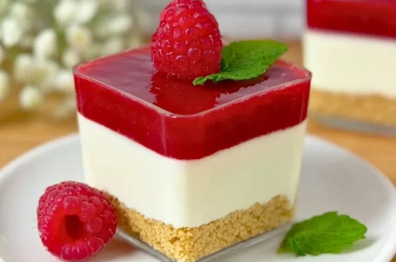 Layered Raspberry Cheesecake in a glass with fresh raspberries and cream