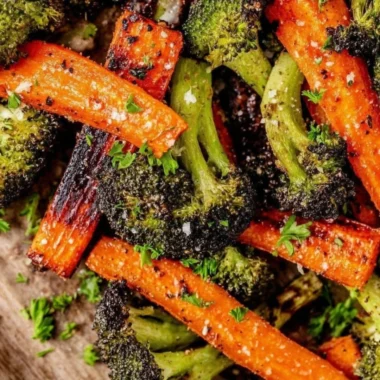 A vibrant bowl of roasted broccoli and carrots garnished with herbs