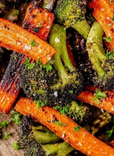 A vibrant bowl of roasted broccoli and carrots garnished with herbs