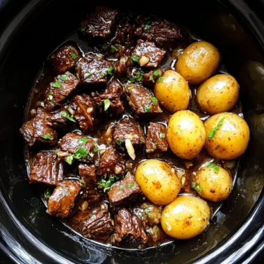 Slow cooker garlic butter beef bites with potatoes in a serving dish