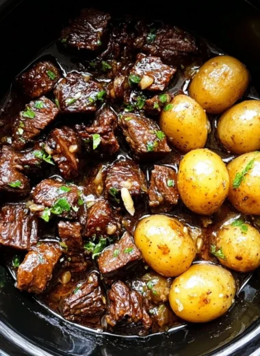 Slow cooker garlic butter beef bites with potatoes in a serving dish