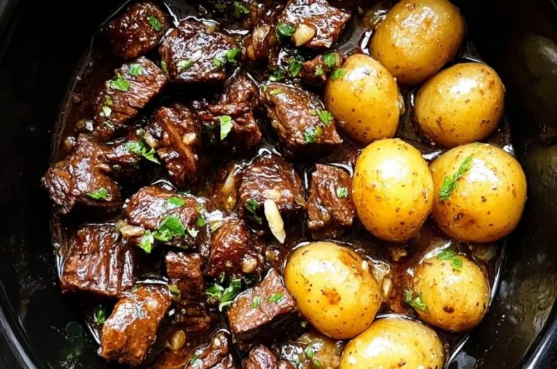 Slow cooker garlic butter beef bites with potatoes in a serving dish